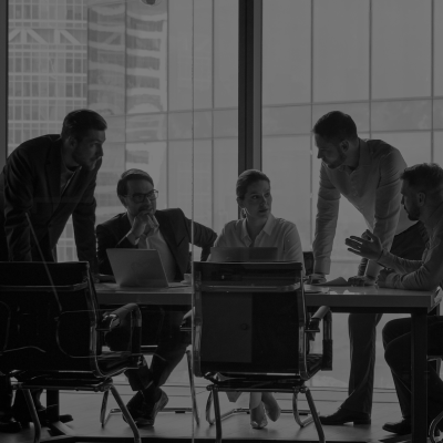 Five people gathered around a meeting room table engaged in conversation.